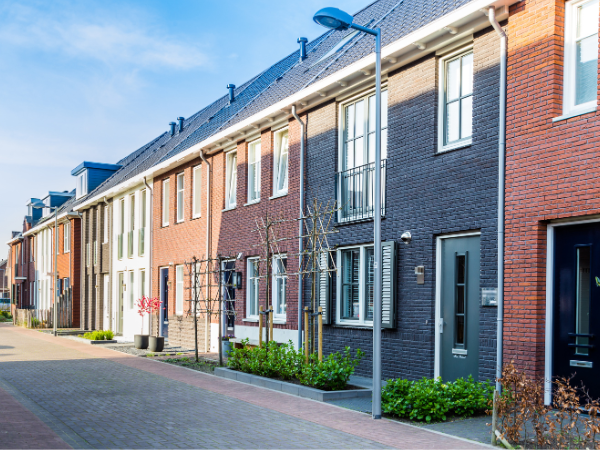 Dit is een foto van een nieuwe klinkeroprit die buiten voor een rij huizen in België werd aangelegd.